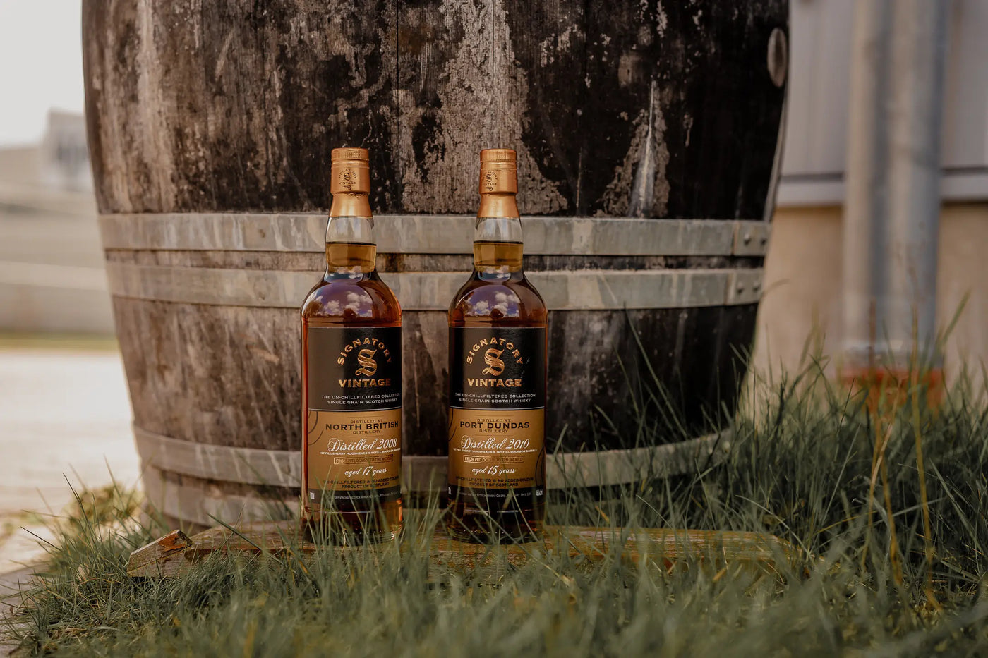 Port Dundas und North Britsh Single Grain Whisky von Signatory Vintage stehen vor einem Holzfass