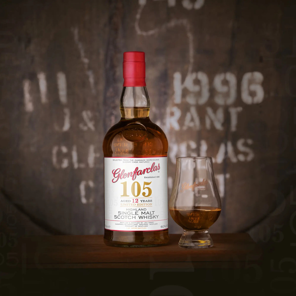 Whiskyflasche Glenfarclas 105 12 Jahre mit halb gefülltem Glas vor einem Glenfarclas Whiskyfass