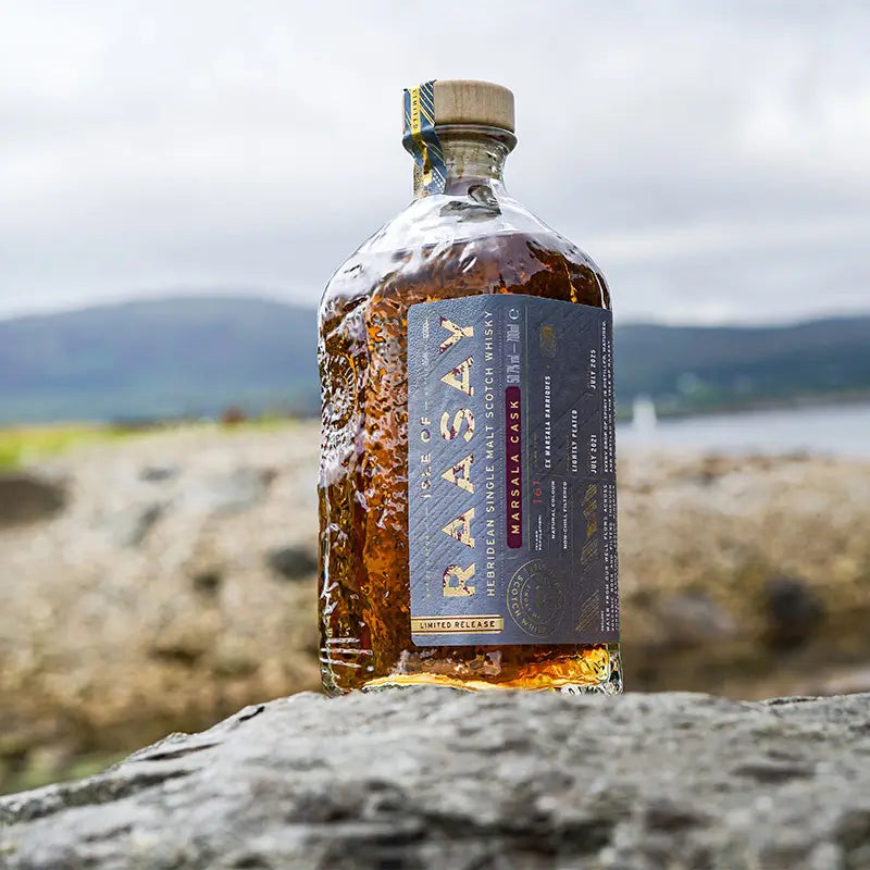 Isle of Raasay Marsala Cask 2021/2025 Single Malt Scotch Whisky auf einem Stein vor der schottischen Küste