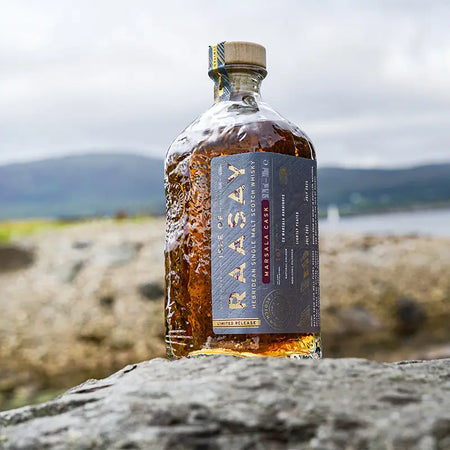 Isle of Raasay Marsala Cask 2021/2025 Single Malt Scotch Whisky auf einem Stein vor der schottischen Küste